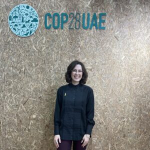 Charlotte stands in front the the COP28 UAE logo